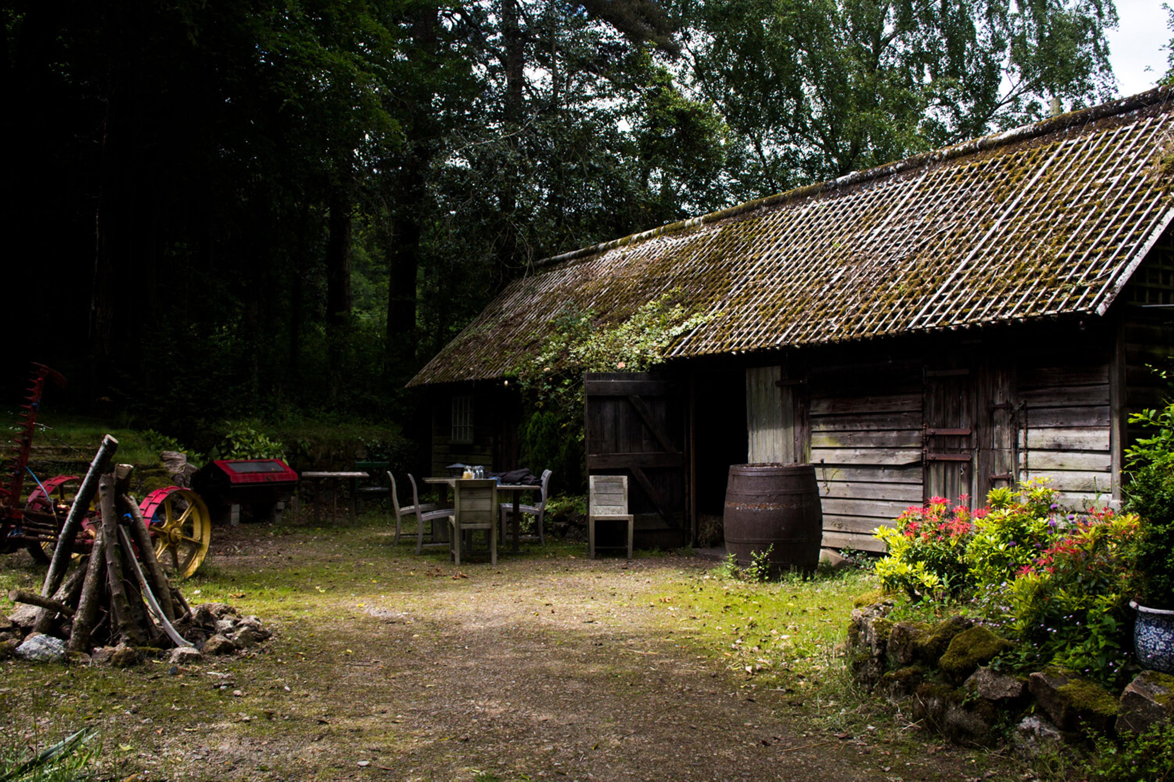 Barn in the woods, with some machinery out in front